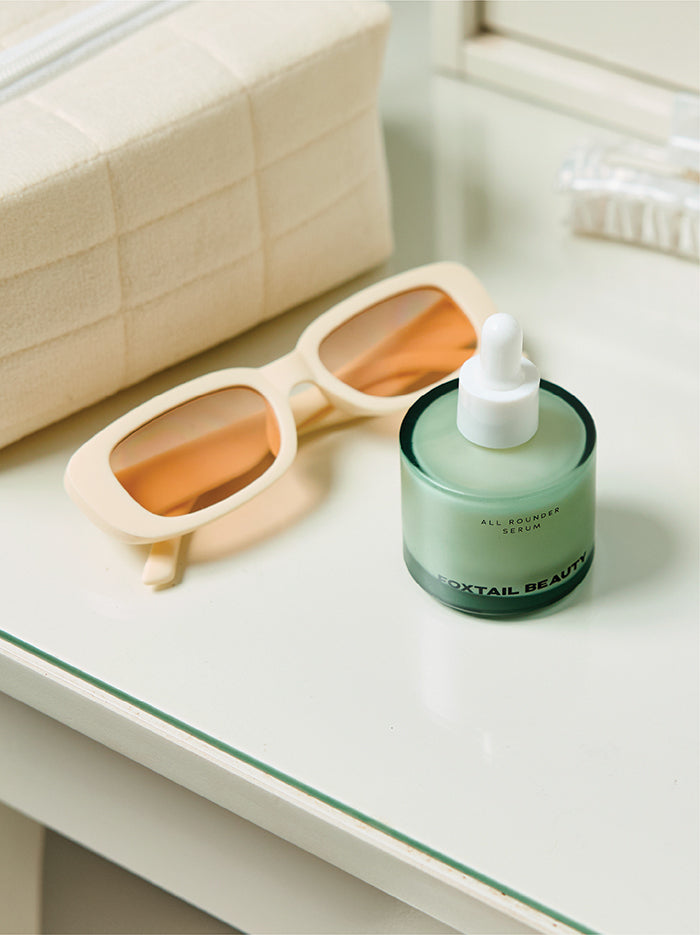 Foxtail Beauty Serum with dropper and sunglasses on a white surface
