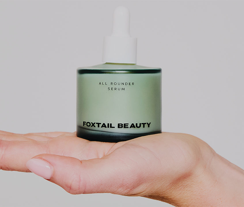 Hand holding calmly and balancing a Foxtail All Rounder Serum on their bare flat hand skin
