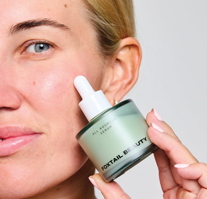 Woman holding a Foxtail Beauty All Rounder serum bottle for fine lines and wrinkles labeled 'Foxtail Beauty'.
