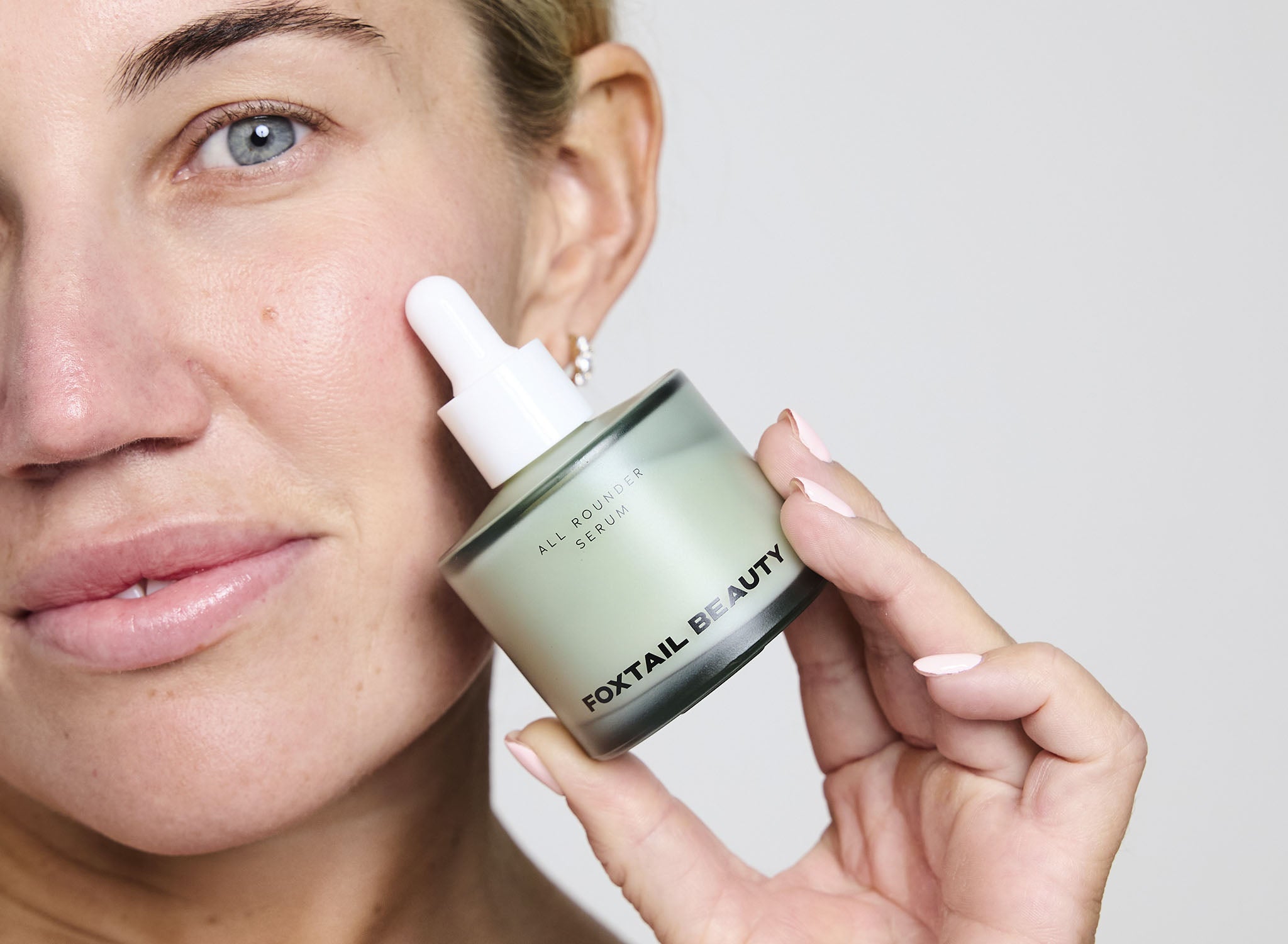 Woman applying Foxtail Beauty All Rounder Serum product from Foxtail & Beauty jar to her face,